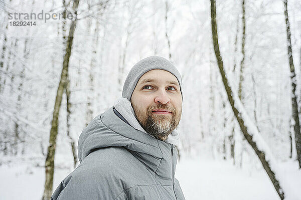 Lächelnder Mann in warmer Kleidung im Winterpark