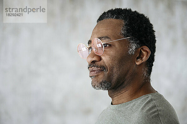 Nachdenklicher reifer Mann mit rosa Brille