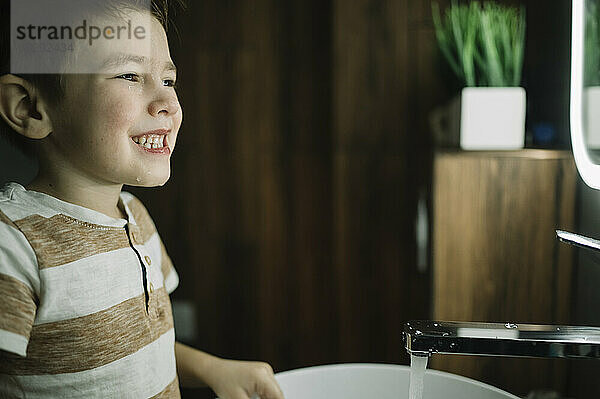 Glücklicher Junge  der zu Hause im Badezimmer steht und Zähne überprüft