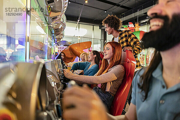 Glückliche junge Frauen  die Spaß mit dem Fahrsimulator in der Spielhalle haben