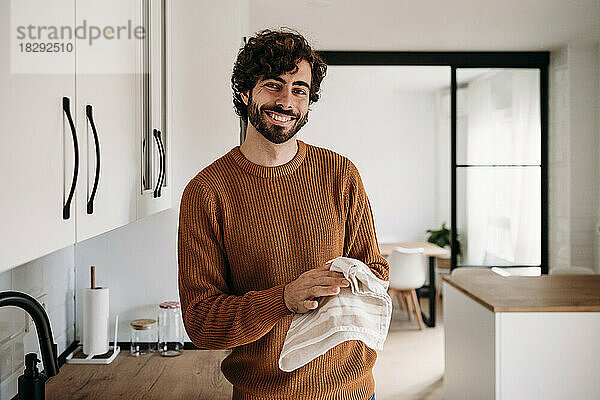Happy young man drying hands with napkin at home