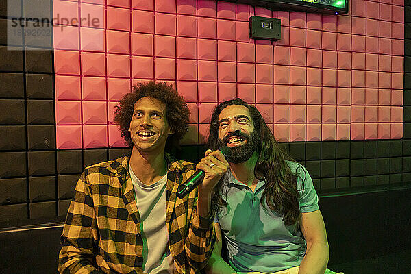 Fröhliche Männer singen Karaoke in der Spielhalle