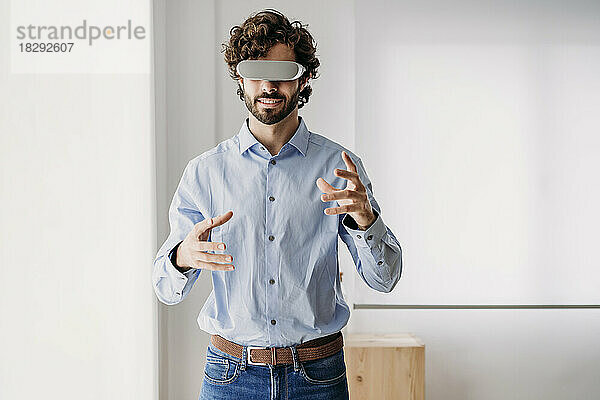 Geschäftsmann mit Virtual-Reality-Brille gestikuliert im Büro