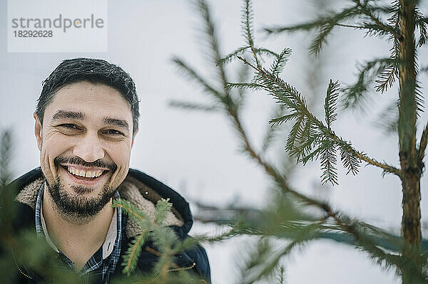 Glücklicher Mann mit Tannenbaum im Schnee