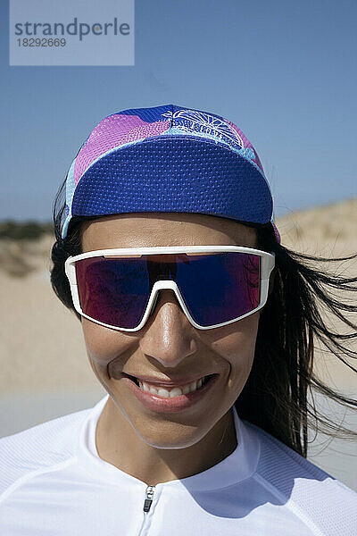 Glücklicher Radfahrer mit Sonnenbrille und Mütze steht an einem sonnigen Tag