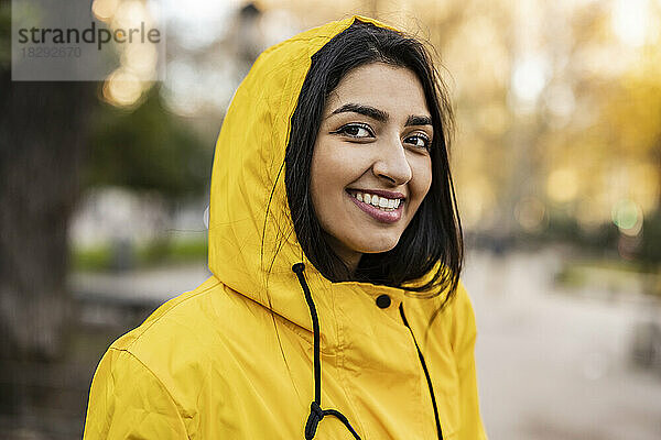Glückliche junge Frau im Regenmantel