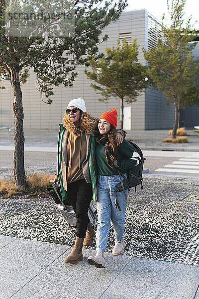 Mutter und Tochter überqueren Straße und ziehen Koffer