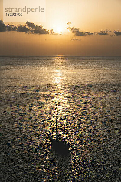 Spain  Balearic Islands  Sun setting over sailboat floating at sea