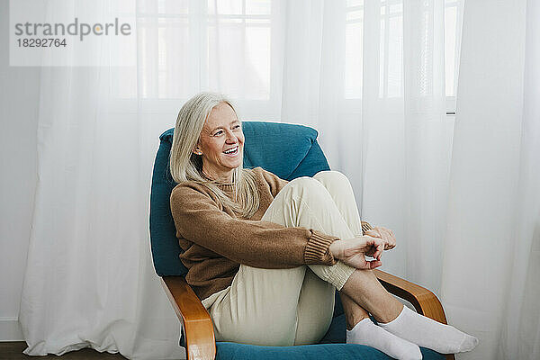 Happy mature woman sitting on armchair