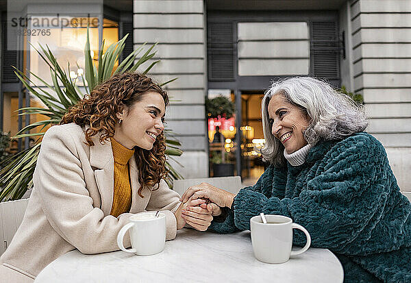 Glückliche Enkelin und Großmutter verbringen Zeit miteinander im Straßencafé