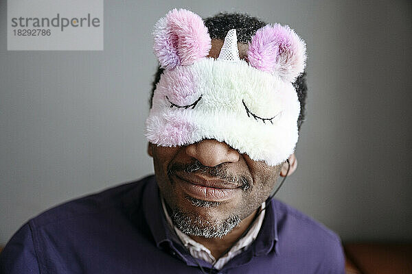 Smiling mature man wearing unicorn eye mask