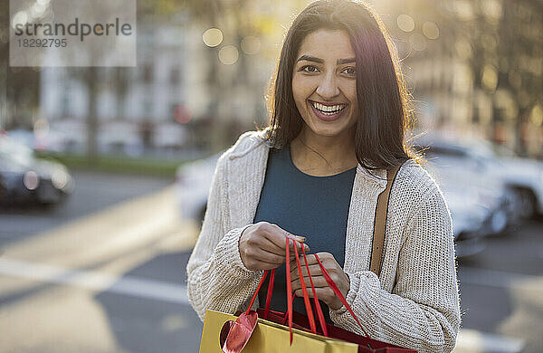 Glückliche junge Frau mit Einkaufstüten an einem sonnigen Tag