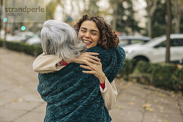 Glückliche Enkelin umarmt Großmutter am Fußweg