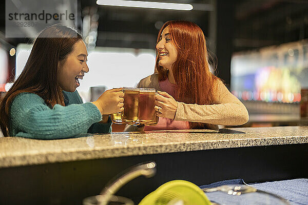 Junge Frauen halten Gläser Bier in der Bowlingbahn