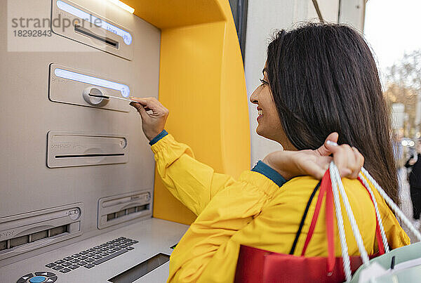 Frau steckt Karte in Geldautomaten ein