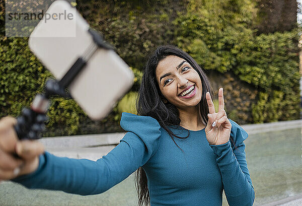 Glückliche Frau  die am Fußweg ein Selfie über ihr Smartphone macht