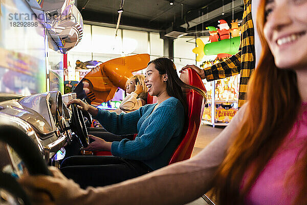 Young women having fun with driving simulator in arcade
