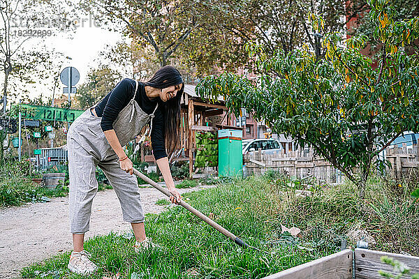 Glückliche Frau bei der Gartenarbeit mit Schaufel im Stadtgarten