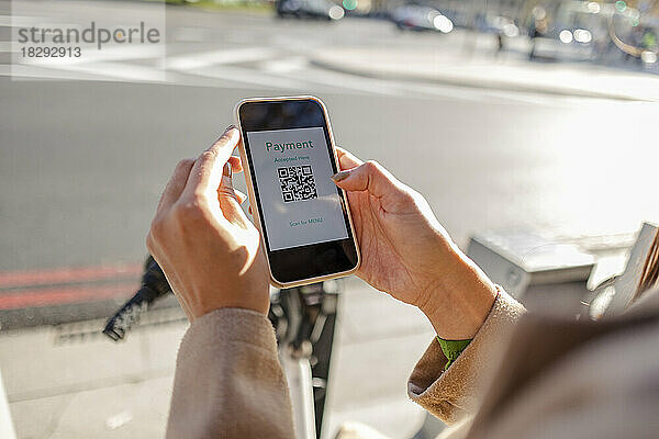 Frau bezahlt kontaktlos per Smartphone  um ein Fahrrad zu mieten