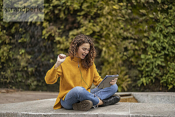 Fröhliche junge Frau jubelt über Tablet-PC