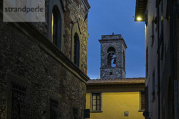 Bell tower and houses in town of Bibbiena at dusk