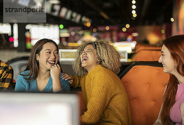 Frau mit Freunden lacht auf der Bowlingbahn