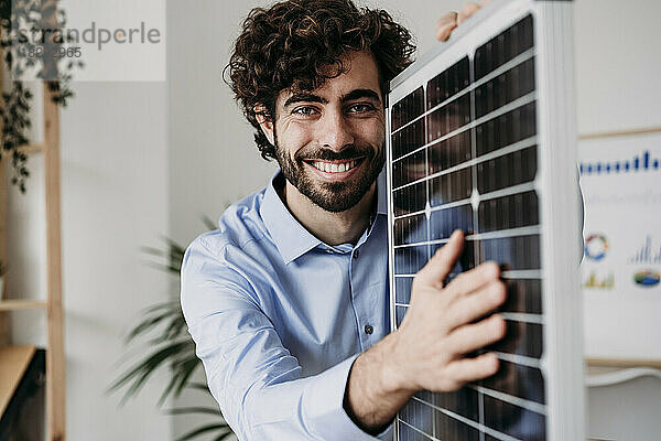 Lächelnder Ingenieur untersucht Solarpanel im Büro