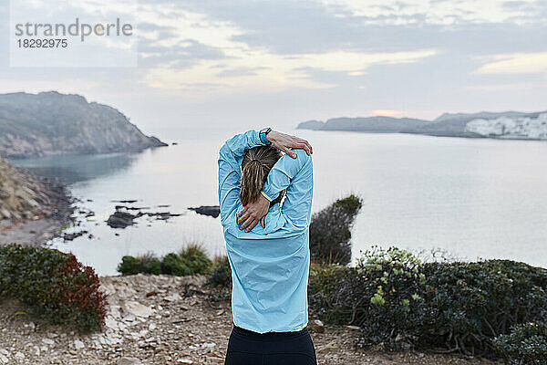 Frau macht Stretching vor dem Meer