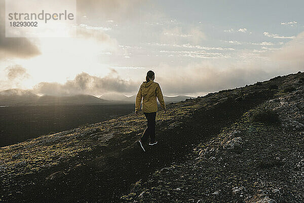 Woman hiking on mountain at sunrise  Caldera Blanca volcano  Lanzarote  Canary Islands  Spain