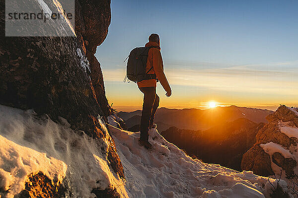 Reifer Wanderer steht bei Sonnenuntergang vor den Bergen