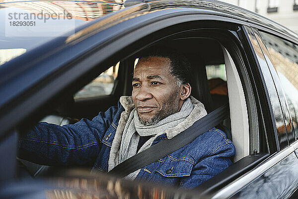 Smiling mature man driving car
