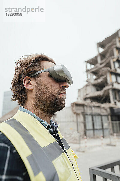 Arbeiter mit Virtual-Reality-Brille steht an der Baustelle