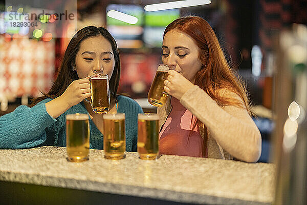 Gemischtrassige Frauen trinken Bier in der Bowlingbahn