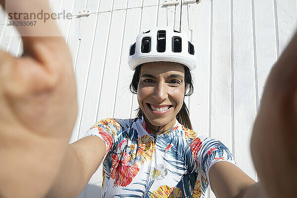 Glücklicher Radfahrer  der Selfie vor der Wand macht