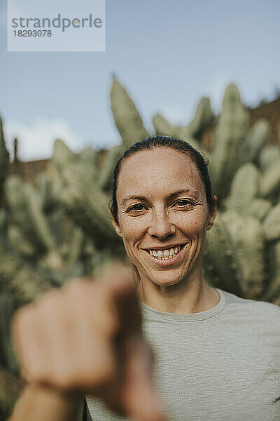 Glückliche Frau gestikuliert im Kaktusgarten