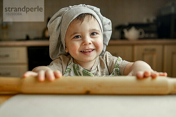 Fröhlicher Junge mit Kochmütze in der Küche