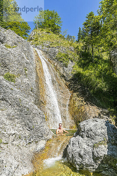 Germany  Bavaria  Male tourist relaxing in small pond of Rappinbach waterfall in summer
