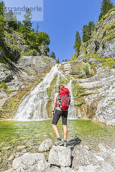 Germany  Bavaria  Female hiker admiring Glasbachwasserfall in summer