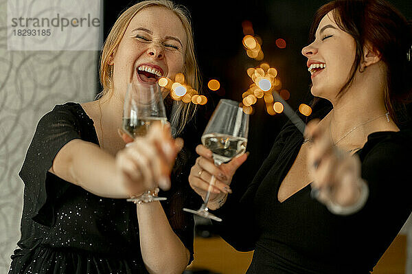 Fröhliche Freunde feiern Weihnachten mit Champagnergläsern und Wunderkerzen
