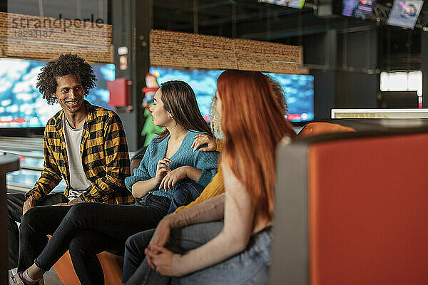 Happy man talking with women at bowling alley