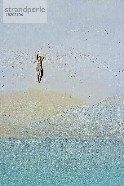 Frau liegt am Strand im Sand