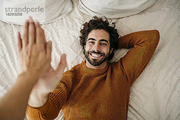 Smiling man giving high-five to friend at home