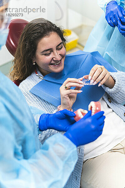 Zahnarzt zeigt glücklichem Patienten in der Klinik Zahnausrichter