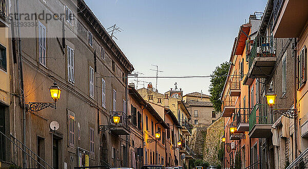 Italien  Latium  Capodimonte  Häuserzeilen und leuchtende Straßenlaternen in der Abenddämmerung