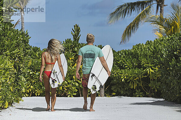 Paar mit Surfbrettern geht zum Strand