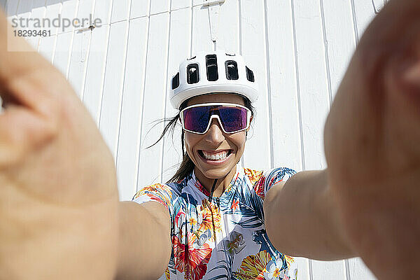 Glücklicher Radfahrer  der an einem sonnigen Tag ein Selfie vor der Wand macht