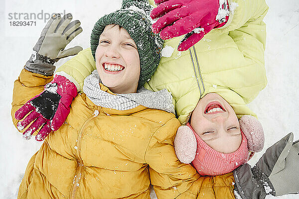 Fröhliches Mädchen mit Bruder genießt den Schnee