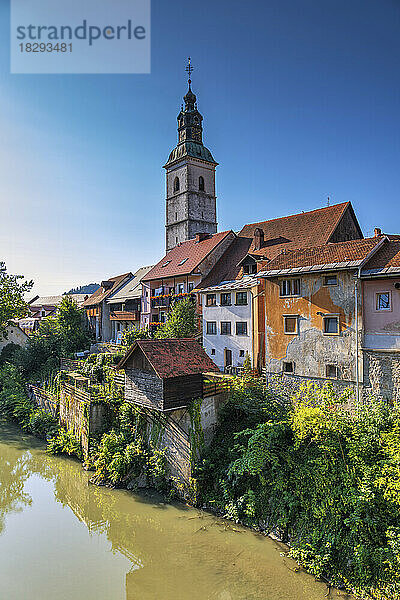Slowenien  Oberkrain  Skofja Loka  Häuser am Flussufer mit Glockenturm der St.-Jakobs-Kirche im Hintergrund