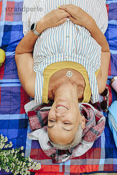 Glückliche ältere Frau  die sich auf einer Picknickdecke hinlegt