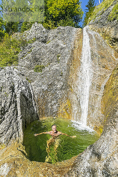 Deutschland  Bayern  männlicher Tourist entspannt sich im Sommer im kleinen Teich des Rappinbach-Wasserfalls